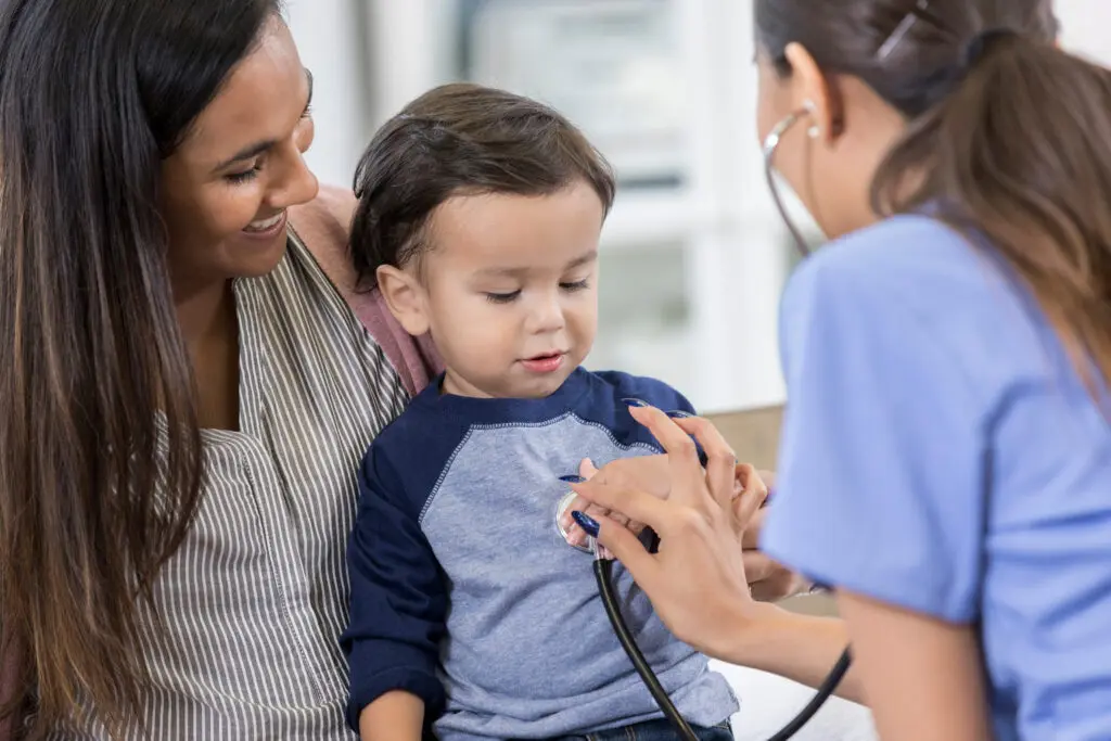 Pediatrician listens to toddler's heartbeat A woman is holding a child and a stethoscope.