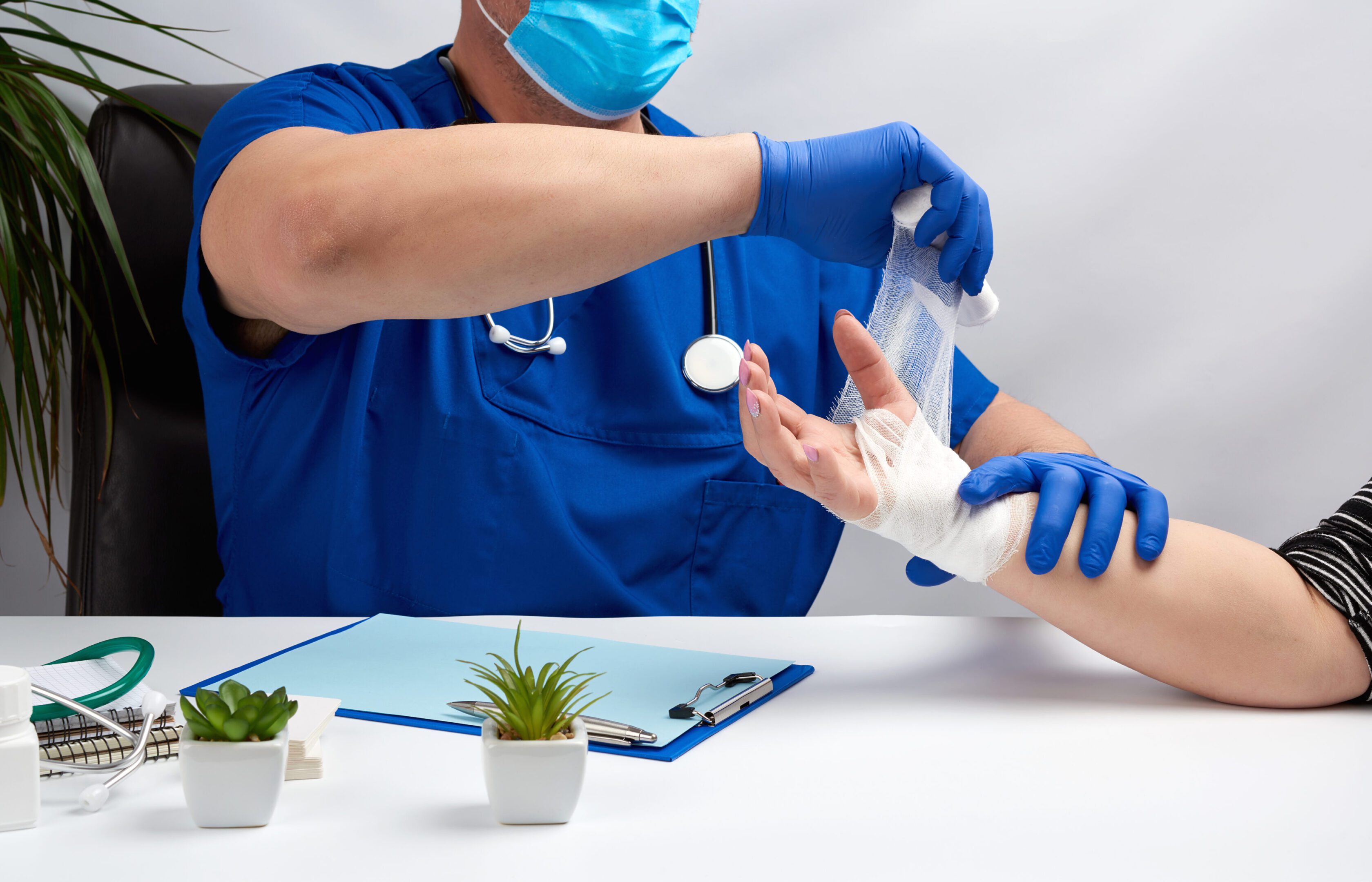 specialist bandages his hand with a white bandage to the patient A doctor is putting something on someone 's hand.